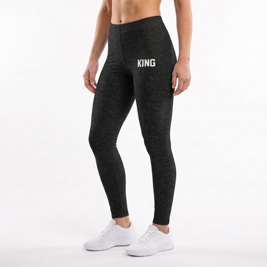 Front three-quarter view of KING APEX Lioness Black Heather leggings with a white KING thigh logo, worn with white sneakers.
