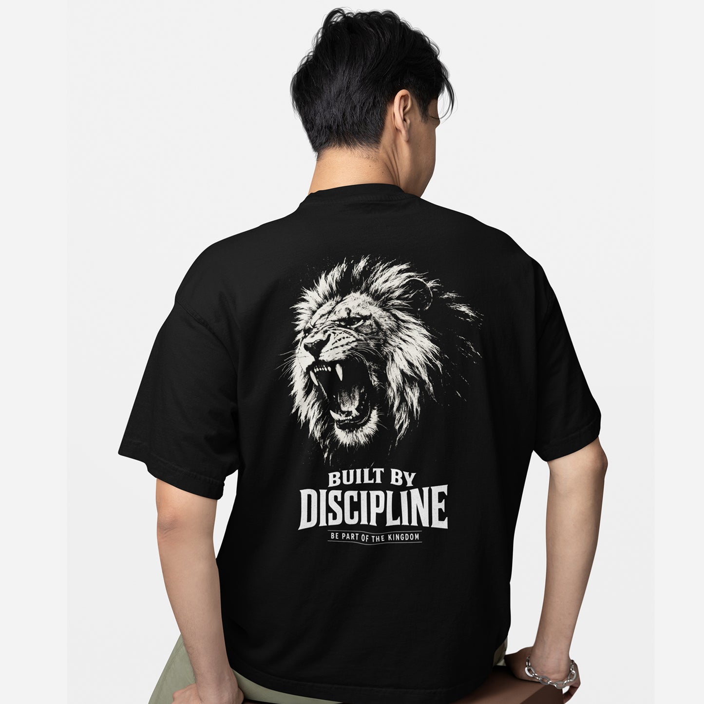 model wearing KING APEX oversized black t-shirt with Built by Discipline lion graphic on back