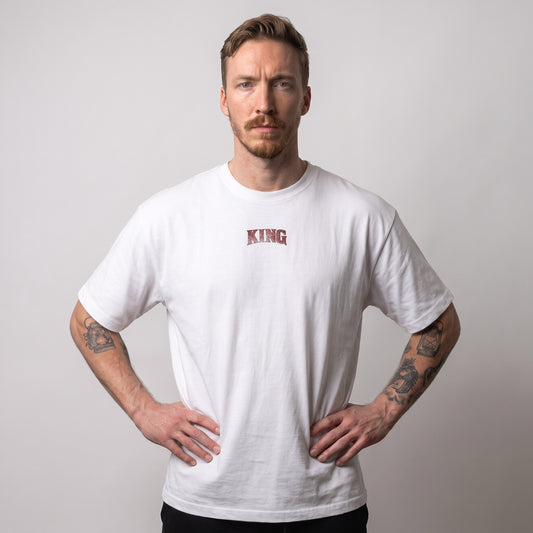 Male model wearing the white KING APEX Power oversized T-shirt, front view with hands on hips and a small red KING chest print.
