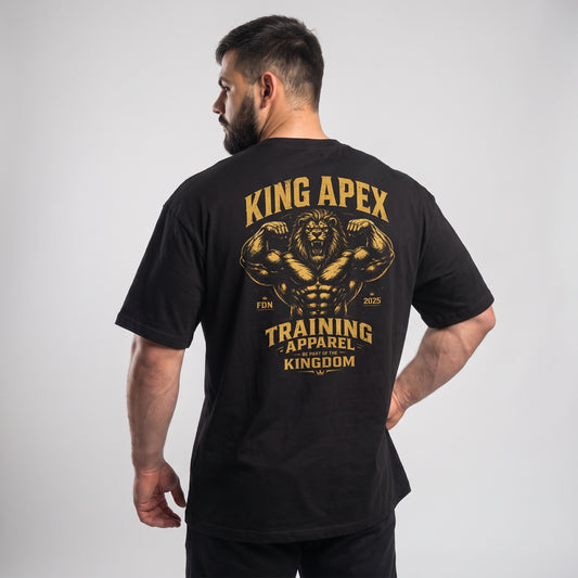 Male model wearing the black KING APEX Training Apparel oversized T-shirt, back view with one hand on the hip showing the gold flexing lion with KING APEX and TRAINING APPAREL lettering.