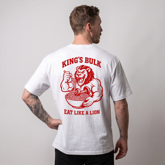 Male model wearing the white KING APEX King’s Bulk oversized T-shirt, back view with one hand on the hip showing the red lion eating pasta with KING’S BULK and EAT LIKE A LION lettering.