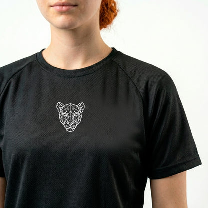 Close-up of minimal lioness logo on KING APEX black sports jersey showing fabric texture and chest detail