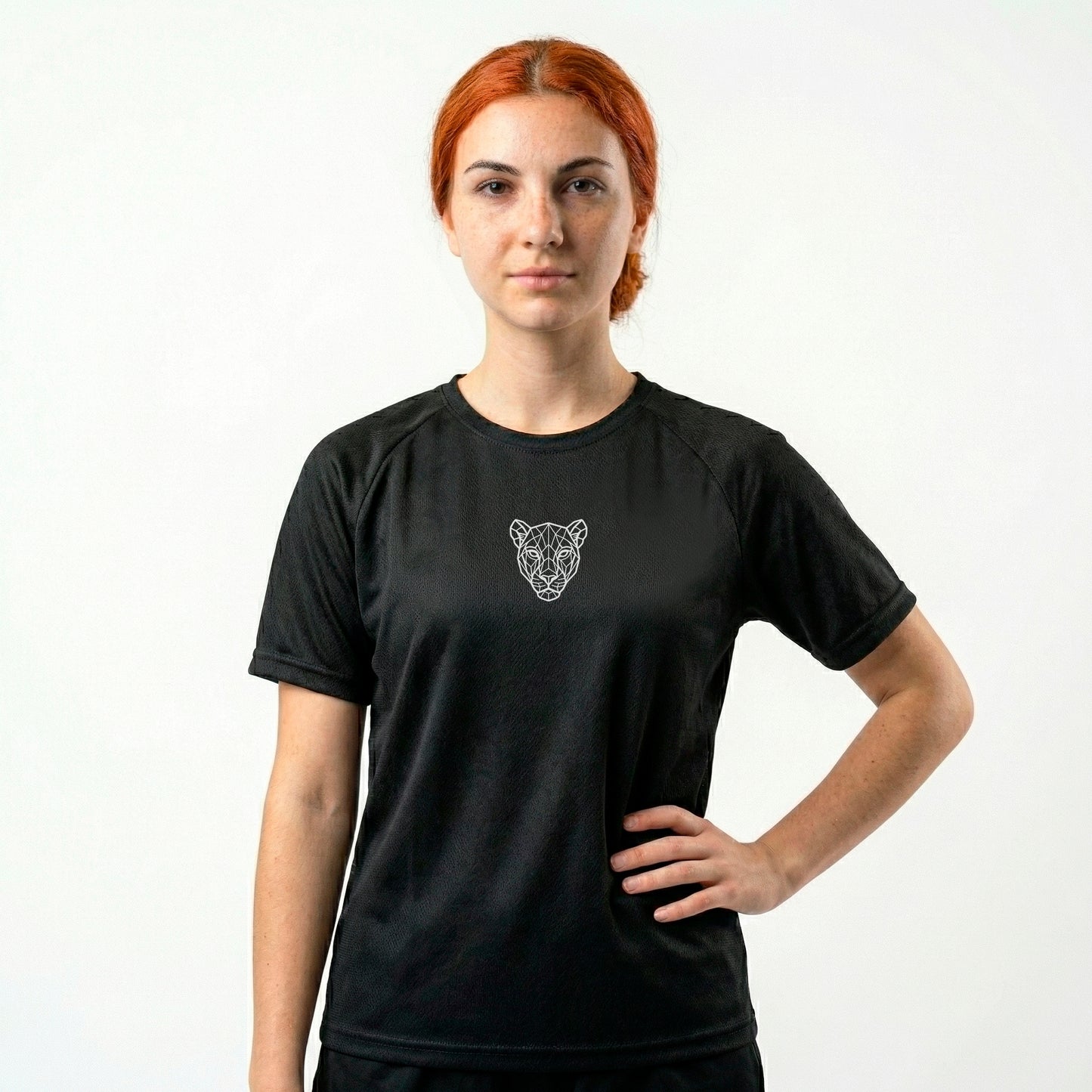 Female model wearing KING APEX black athletic sports jersey with minimal lioness logo hand on waist pose