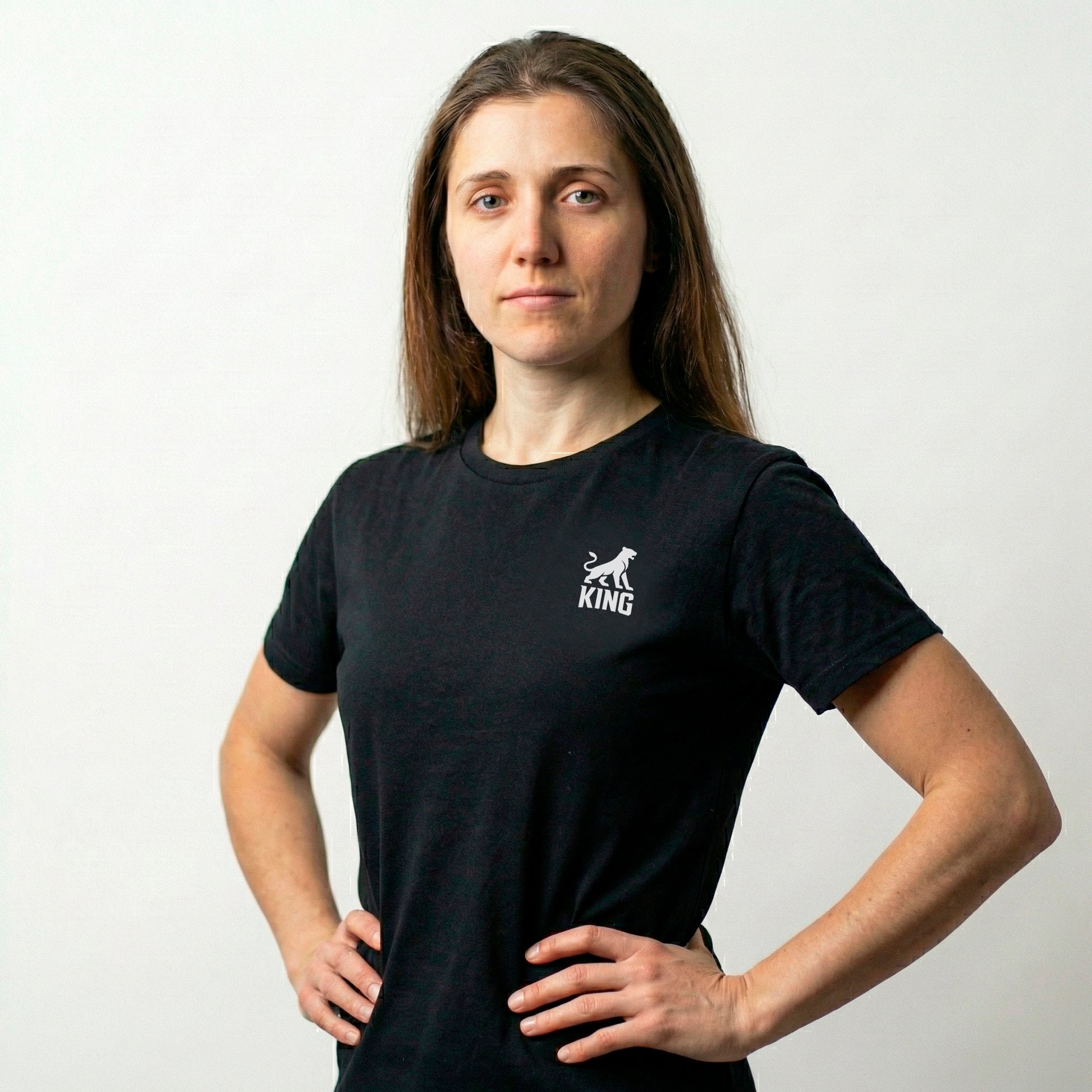 Woman wearing KING APEX black sports tee with minimal lioness logo on chest