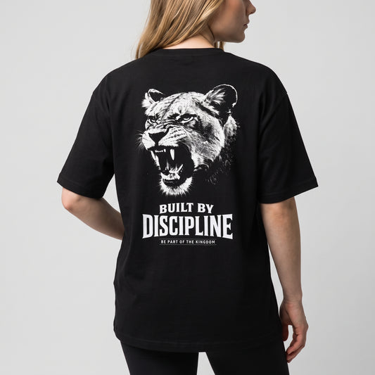 Close back view of the black KING APEX Lioness Built by Discipline oversized T-shirt on a female model, showing the white roaring lioness portrait with BUILT BY DISCIPLINE lettering.