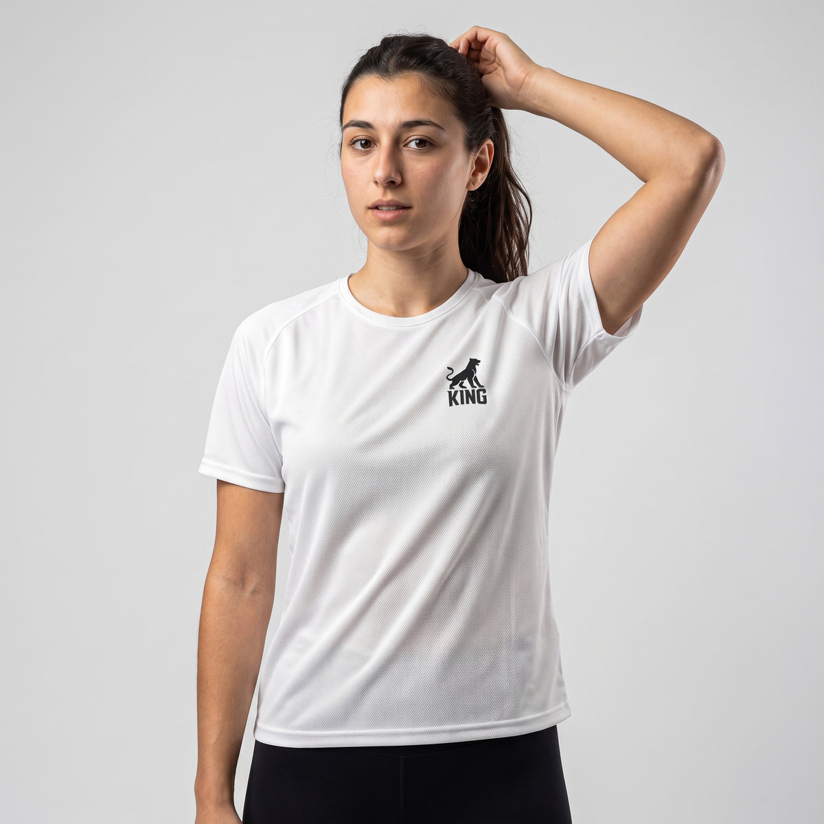 Front view of woman wearing the white KING APEX Lioness sports jersey with geometric lioness chest logo.