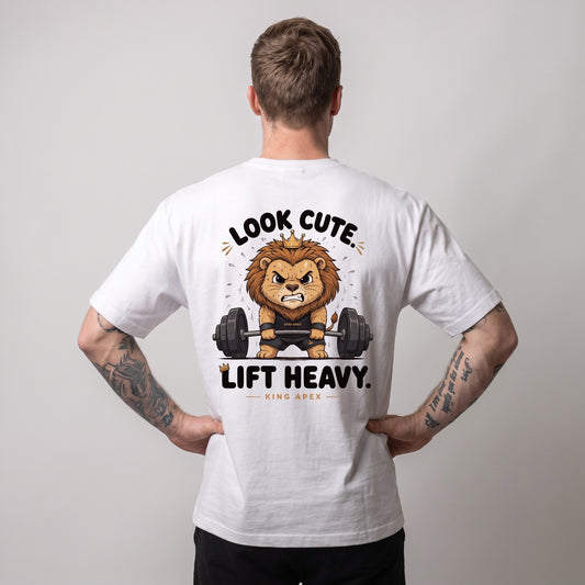 Male model wearing the white KING APEX Look Cute. Lift Heavy. oversized T-shirt, back view with hands on hips showing the crowned cartoon lion lifting a barbell with LOOK CUTE. LIFT HEAVY. lettering.