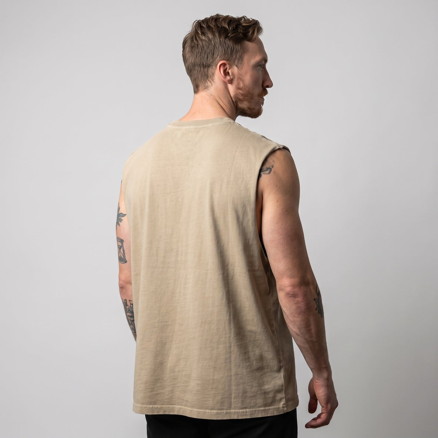 Three-quarter back view of the KING APEX Men's Heavy Faded Tank in sand, highlighting its loose straight-cut fit and heavyweight drape.