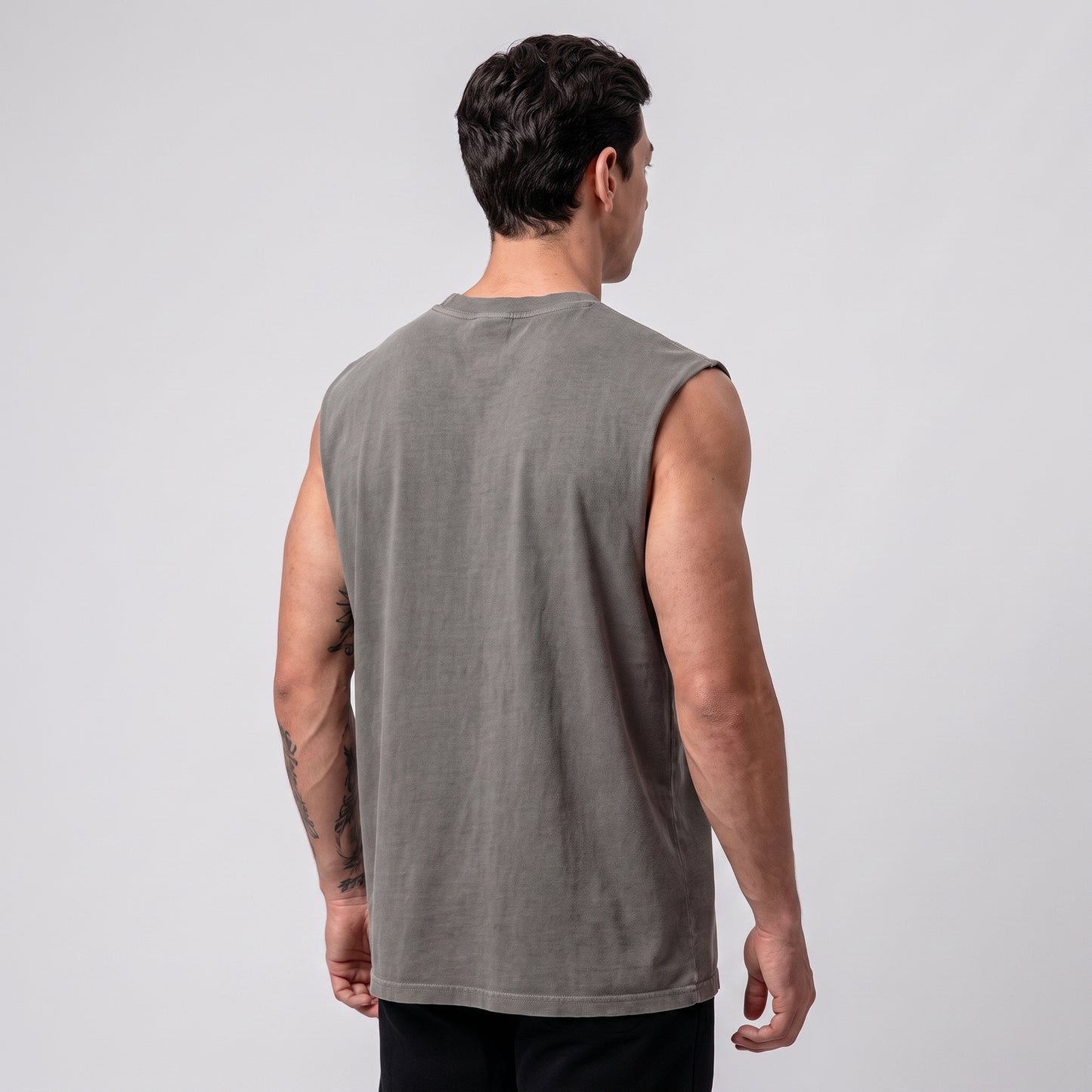 Male model wearing the KING APEX Men's Heavy Faded Tank in Stone Grey, alternate three-quarter back view.