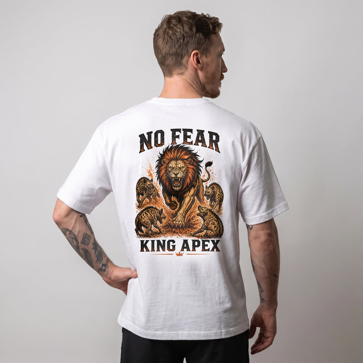 T-shirt oversize blanc KING APEX No Fear porté par un modèle masculin de dos, une main sur la hanche et le motif lion visible.