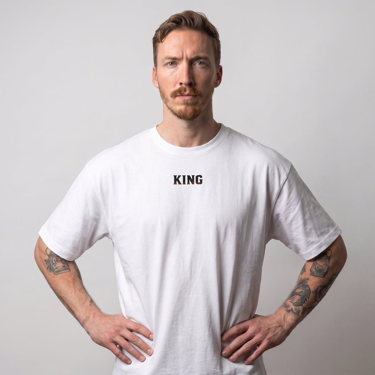 Vue rapprochée de face d'un modèle masculin portant le t-shirt oversize blanc KING APEX No Fear, avec le petit logo KING noir sur la poitrine.