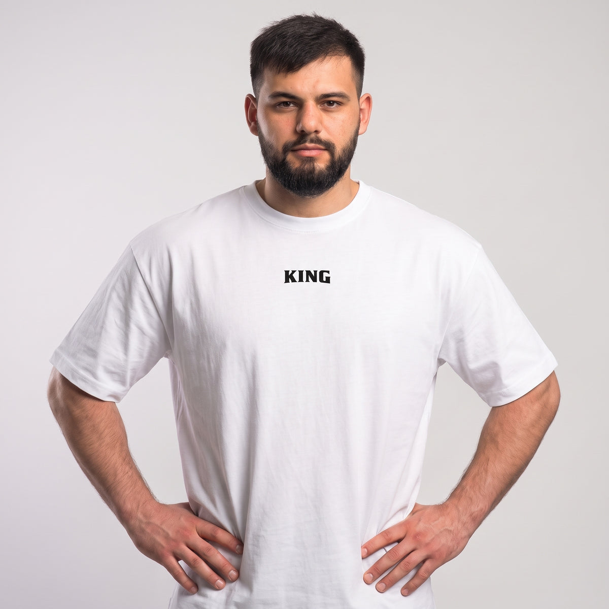 Male model wearing the white KING APEX Off-Season oversized T-shirt, front view showing the small black KING chest print.