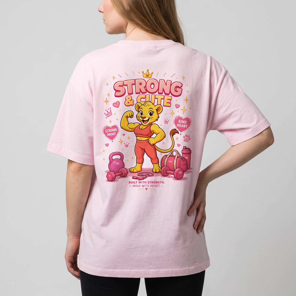 Angled rear view of the KING APEX Soft Pink oversized T-shirt with a cartoon lioness, hearts and gym equipment.