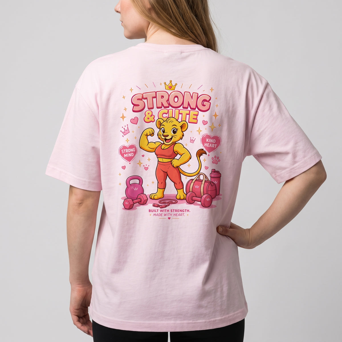 Woman wearing the KING APEX Soft Pink oversized T-shirt, showing the Strong & Cute lioness graphic on the back.