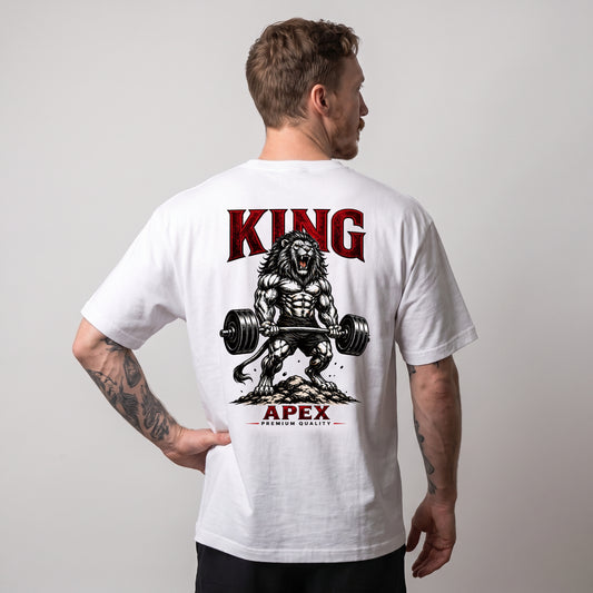 Male model wearing the white KING APEX Power oversized T-shirt, showing the barbell lion graphic and red KING and APEX lettering on the back.