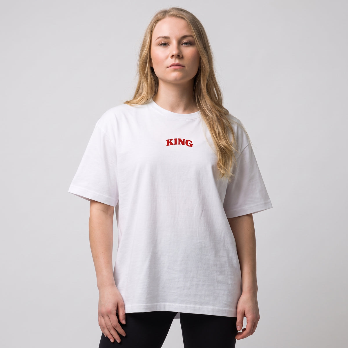Female model wearing the white KING APEX Queen’s Bulk oversized T-shirt, front view showing the small red KING chest print.