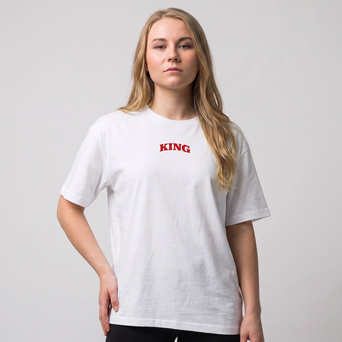 Female model wearing the white KING APEX Queen’s Bulk oversized T-shirt, front view showing the small red KING chest print.