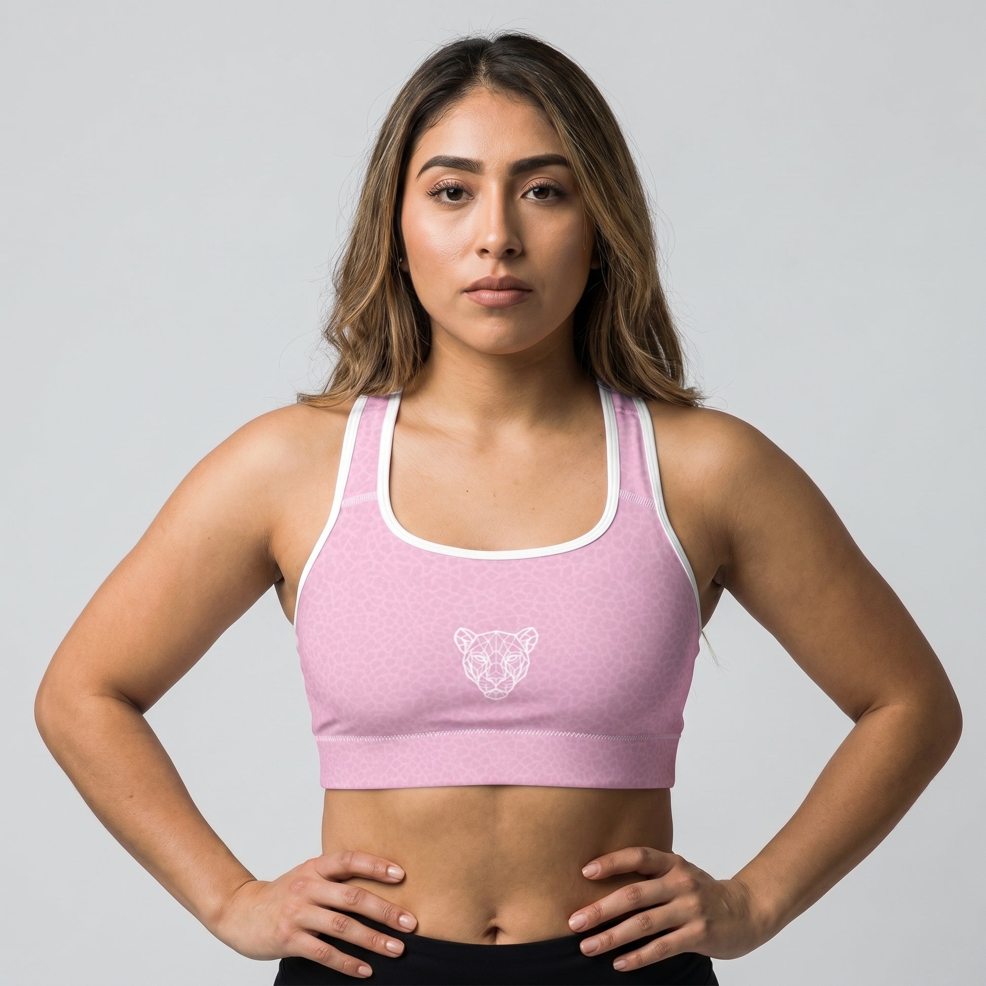 Female athlete wearing KING Lioness Sports Bra Rose Scale Edition in pink geometric lioness pattern, front view