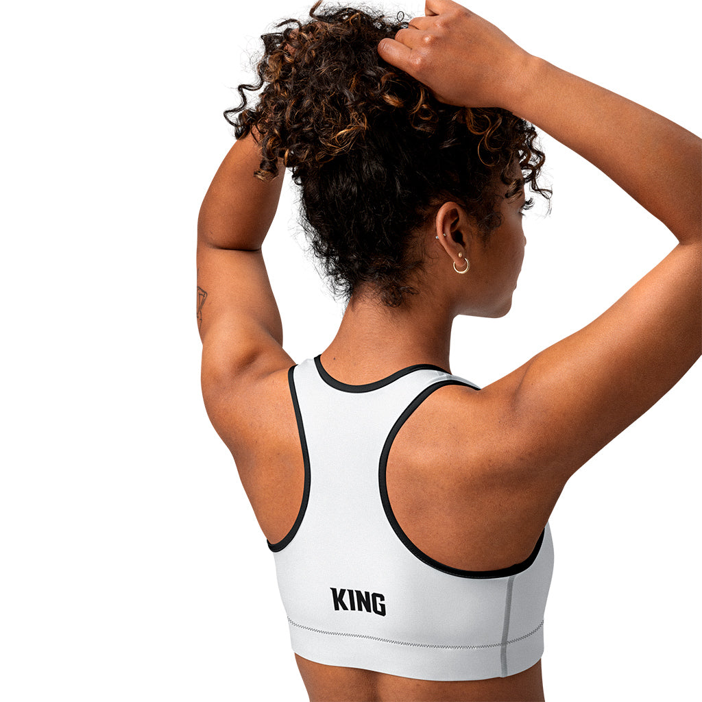 White KING Lioness sports bra with black piping – side view with geometric lioness emblem.
