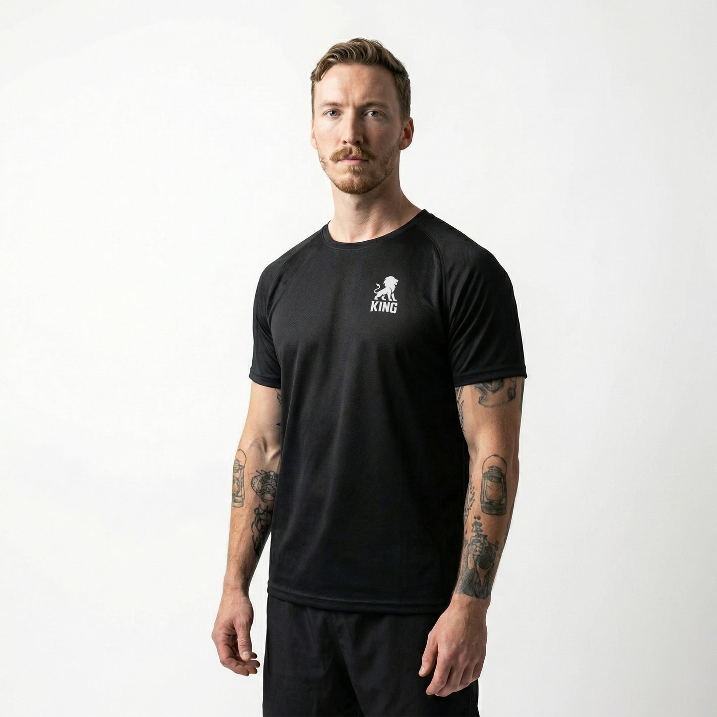 Male model wearing KING Sports Jersey Black with Minimal Lion Chest logo, full body side view, performance sportswear
