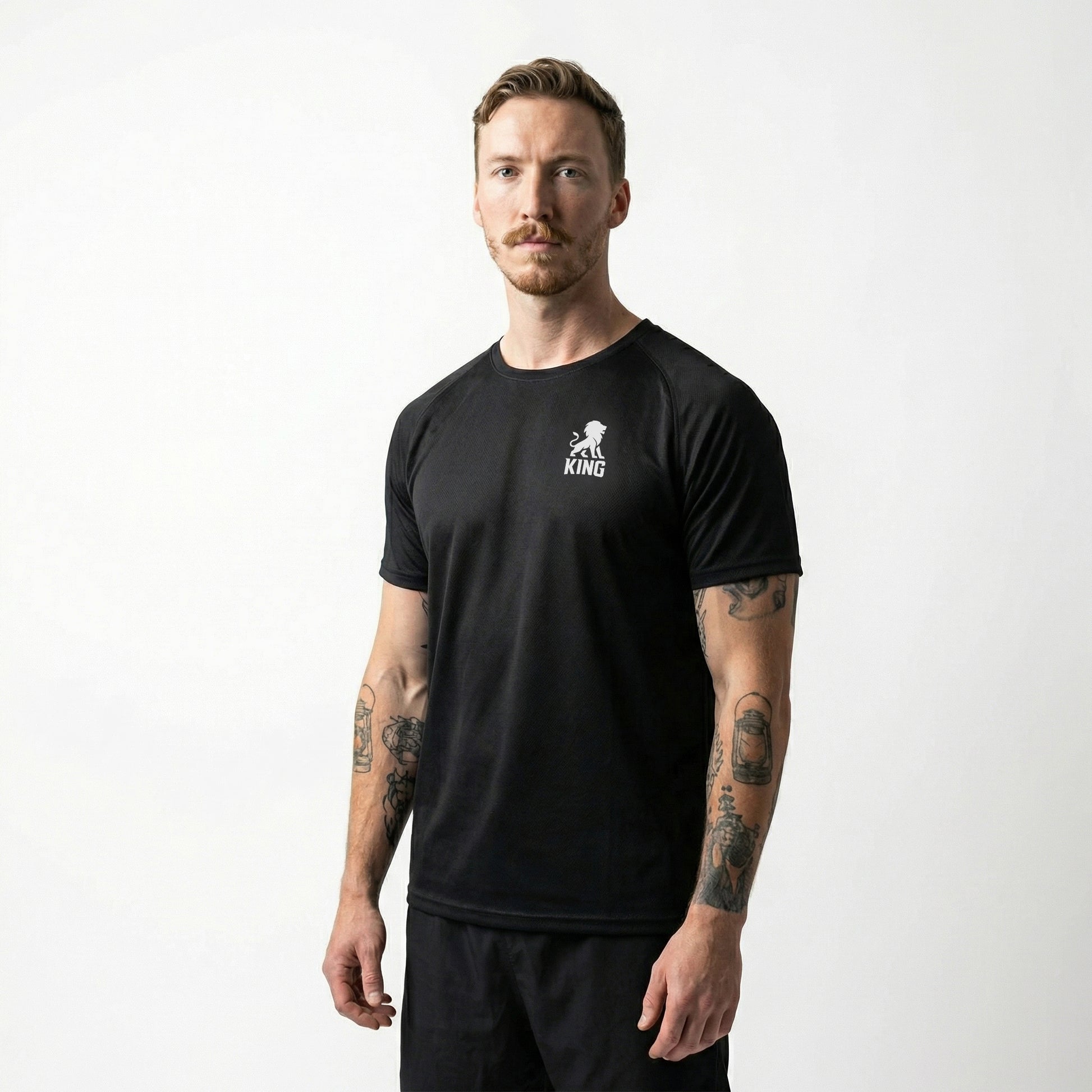 Male model wearing KING Sports Jersey Black with Minimal Lion Chest logo, full body side view, performance sportswear