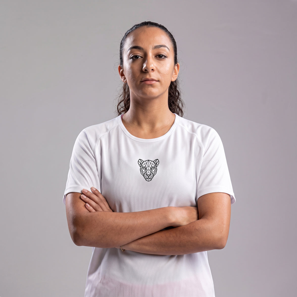 Woman modeling white KING Sports Jersey with arms crossed, geometric lioness logo detail