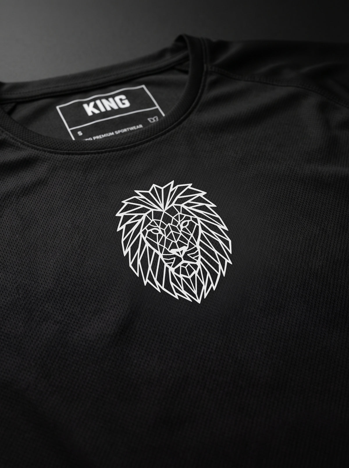 Close-up of the geometric Lion emblem on a black KING APEX shirt
