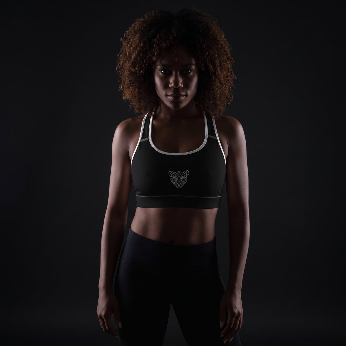 Model wearing the black KING APEX Lioness sports bra with white trim