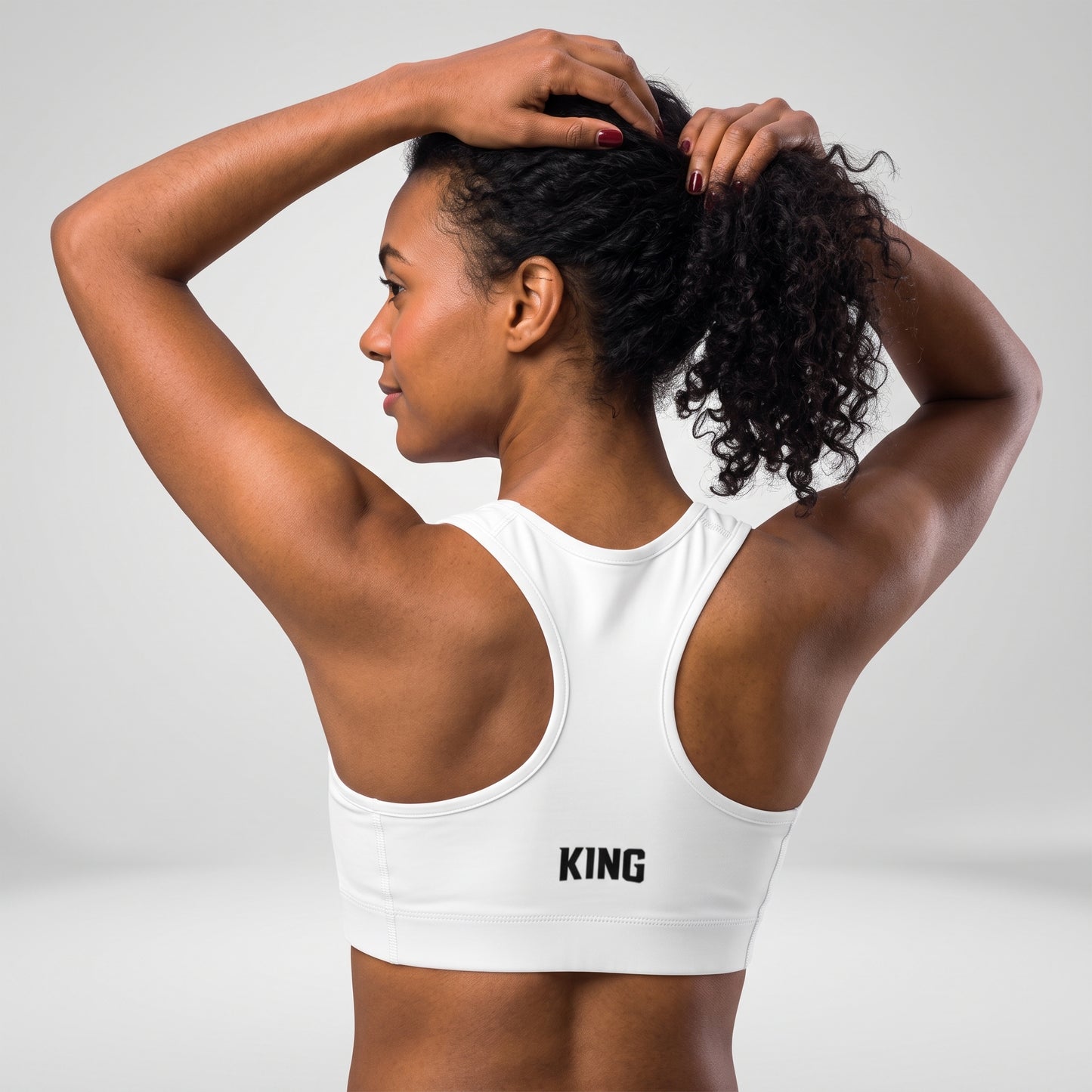 Angled back view of the KING Lioness Sports Bra in black on a female model.