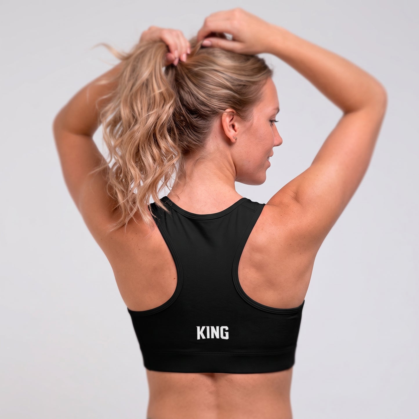 Back view of the KING Lioness Sports Bra in black on a female model.