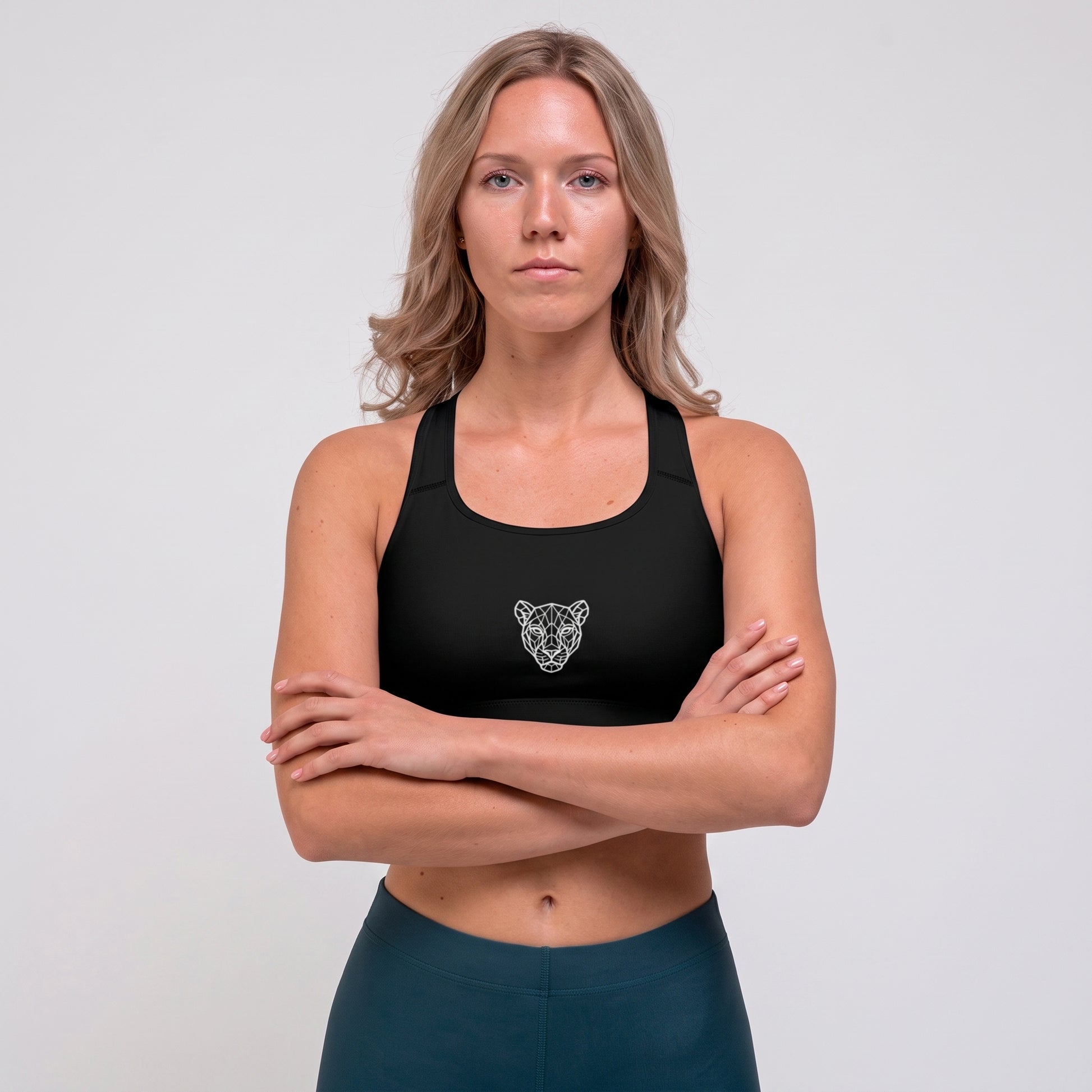 Woman wearing the KING Lioness Sports Bra in black with arms crossed, front view.