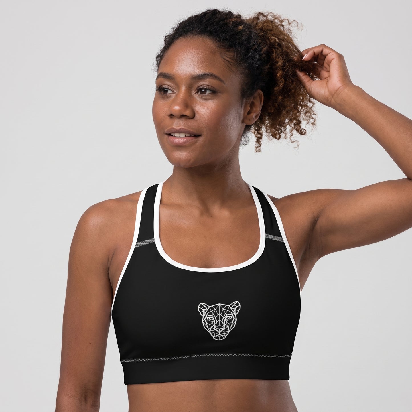 Angled front view of the KING Lioness Sports Bra in black with white piping on a female model.