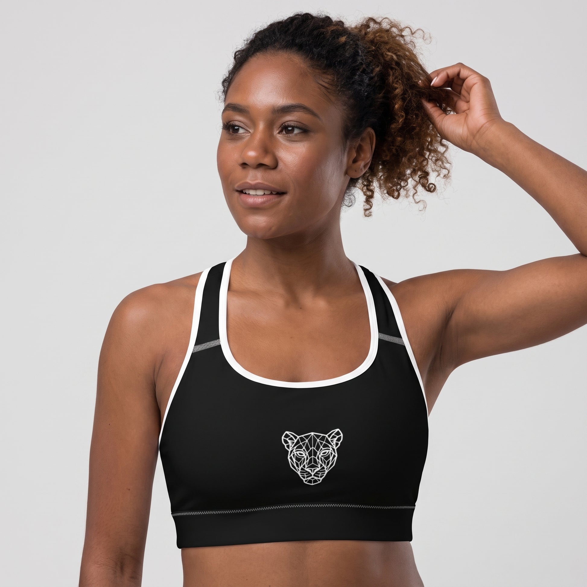 Angled front view of the KING Lioness Sports Bra in black with white piping on a female model.