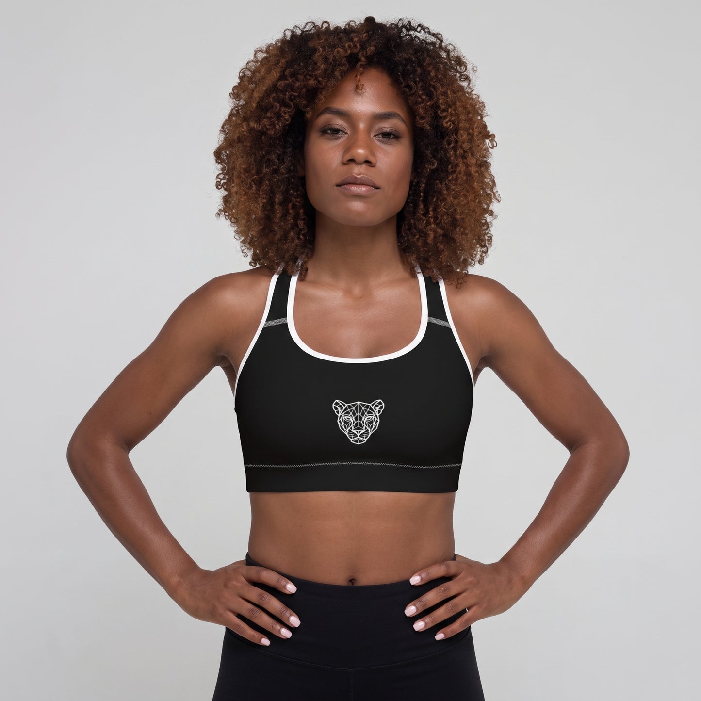 Woman wearing the KING Lioness Sports Bra in black with white piping, front view.