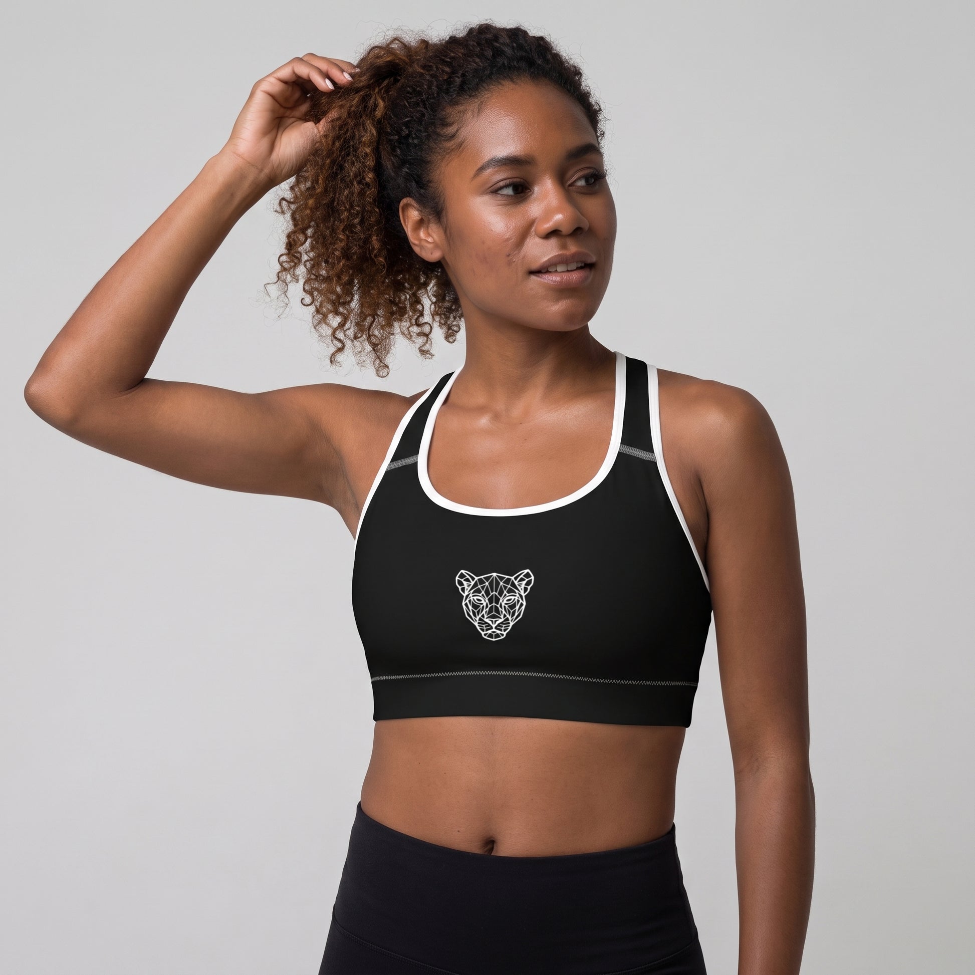Female model wearing the KING Lioness Sports Bra in black with white piping.
